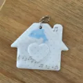 Close-up detail of cute house-shaped photocard holder with blue dolphin design and heart window. - Dolphin House / Blue & White