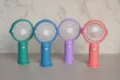 Primo piano di mini ventilatori portatili con base di ricarica in colori pastello. - Stile Semplice