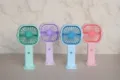 Vista dettagliata del mini ventilatore portatile con quattro varianti colorate e base. - Stile Semplice