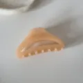 Vue détaillée d'une pince à cheveux en acrylique rose pèche au design épuré creux. - Pince à Cheveux Arc Ajouré / Orange