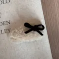 Nahaufnahme einer flauschigen Schleifen-Haarspange mit weichem Plüsch und schwarzer Schleife. - Beige Schleife Haarklammer