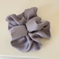 Close-up detail of a soft satin hair scrunchie in pastel purple, highlighting smooth glossy finish. - Greyish Purple Hair Tie