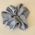 Close-up detail of large grey satin hair scrunchie, smooth glossy fabric for daily hair styling. - Blue Scrunchie