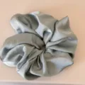 Detail shot of a light blue satin scrunchie, showcasing smooth glossy fabric and fluffy texture. - Dark Green Scrunchie