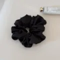 Close up of black satin scrunchie detail, smooth fabric texture, elegant hair accessory for daily use. - Black