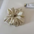 Close-up of a smooth satin hair scrunchie in cream color, gentle for daily styling. - Yellow