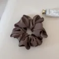 Detailed shot of a sleek brown satin scrunchie, elegant and smooth hair accessory. - Brown