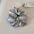 Detailed close-up shot of the elegant silver satin hair scrunchie with smooth soft texture. - Blue