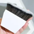 Gros plan du pinceau de maquillage blanc pour fond de teint aux poils denses et ondulés. - Blanc