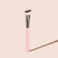 Detailed shot of angled makeup brush with soft synthetic bristles and pink handle for smooth. - Pink