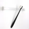 Detail shot of soft bristle toothbrush with portable clear storage case, clean design. - Black Handle Flat Head