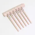 Detail view of the 6-piece pink makeup brush set with elegant round storage container. - Off White