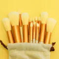 Professional makeup brush set with gold ferrules and soft bristles in a storage pouch. - Yellow