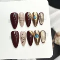 Handgefertigtes künstliches Nagelset mit elegantem Bordeauxrot, Goldglitter und blauem Schmuckstein. - Extra Klein (XS) / 10 Stück / Weinroter Goldfolien-Schmuckstil (W466)
