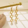 Detalle en primer plano de pendientes colgantes de trébol de acero inoxidable dorado. - Estilo Dorado (MY546)