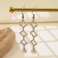 Primer plano detallado de pendientes de acero inoxidable con trébol y perlas colgantes. - Estilo Plateado (MY546-1)