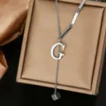 Detailed close-up of a stainless steel initial G letter Y necklace on a luxury gold jewelry box. - Letter G Style (WY006-1-G)