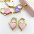 Gros plan de fermoirs mousquetons en cœur colorés, anneaux à ressort émaillés bijoux DIY. - Accessoire Seul / Rose Clair