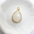 Detailaufnahme eines tropfenförmigen weißen Stein-Anhängers mit Zirkonia in Gold. - Weiß
