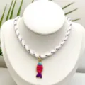Gros plan détaillé du collier pendentif poisson émaillé coloré sur un support blanc. - Pendentif + Chaîne sur la Photo (Q01-18)