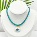 Primer plano detallado del collar con colgante de esmalte de golondrina azul vintage con borde. - Colgante Pájaro Ovalado Con Cordón Azul Verde