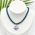 Detalle de cerca del collar de cordón azul con colgante ovalado esmalte blanco huella de pata. - Colgante Pata de Gato Ovalado Con Cordón Azul Oscuro