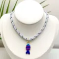Vue détaillée du pendentif poisson coloré et rayé sur un collier en corde tressée. - Pendentif + Chaîne sur la Photo (Q01-13)