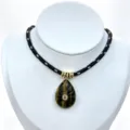 Close-up detail of teardrop carved gemstone pendant with central zircon on black braided necklace. - Pendant With Chain / Black and White