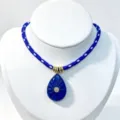 Detail view of blue carved teardrop pendant necklace with braided rope chain and central stone. - Pendant With Chain / Blue