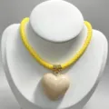 Detail view of the yellow woven rope necklace featuring a glossy beige heart pendant. - B05 Finished Necklace / Yellow Cord with Beige Heart