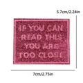 Pink glitter embroidered patch with funny text slogan measuring 7x5.7cm for clothing. - Pink Black Too Close (PE16517CT)
