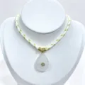Detailed view of carved crystal teardrop pendant necklace with gold rings and woven rope. - Pendant With Chain / Green/White