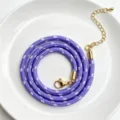 Nahaufnahme der lila geflochtenen Kordelkette mit goldenem Verschluss und Kettchen. - C01-28