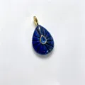 Natural stone teardrop carved pendant with center blue gemstone and gold-tone bail accessory. - Lapis Lazuli Color