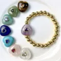 Nahaufnahme eines Goldperlenarmbands mit einem lila Herz Edelsteinanhänger auf weißem Teller. - Armband-Stil / Armbandlänge ca. 17cm / J08 Amethyst (Armband)