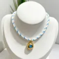 Detailed close-up view of the irregular gold plated pendant necklace with blue stone. - Necklace (With Pendant and Chain) / Blue and White Braided Rope