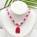Close-up detail of the pink and white patterned rope necklace with a cute enamel house pendant. - Pendant With Chain (E02-1)