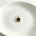 Nahaufnahme eines minimalistischen vergoldeten quadratischen Anhängers mit schwarzem Zirkon. - Quadratisch Schwarz