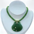 Nahaufnahme der geschnitzten grünen Muschel Anhänger Halskette mit goldenen Akzenten. - Halskette (Anhänger Mit Kette) / Grün
