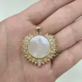 Detailed close-up of gold sunburst pendant featuring white mother-of-pearl and zirconia. - White Shell Round Plate (B1-01)