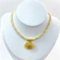 Primo piano dettagliato della collana in corda intrecciata gialla con ciondolo ovale e anelli d'oro. - Set Collana con Ciondolo / Giallo