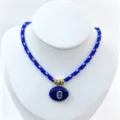 Vista dettagliata della collana in corda blu con ciondolo ovale scanalato e pietra, accessorio. - Set Collana con Ciondolo / Blu scuro