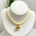 Close-up detail of the gold irregular pendant and yellow braided cord necklace elegant. - Necklace (With Pendant and Chain) / Yellow and White Braided Rope