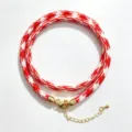 Gedetailleerde opname van de rood-witte houndstooth geweven touwketting met gouden hardware. - A-14