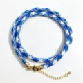 Detailopname van het blauw-witte geweven koord met gouden karabijnsluiting en ketting. - A-13