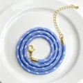 Detailaufnahme der blau-weißen geflochtenen Kordelkette mit goldenem Karabinerverschluss. - C01-8