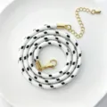 Detailaufnahme einer 3mm schwarz-weißen Polyester Rundschnur Kette mit goldener Hardware. - C01-6