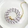 Detailaufnahme der 3mm Kordel, weiß-lila geflochten mit goldenem Karabiner und Verlängerungskette. - C01-3