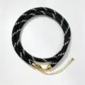 Black and white braided cord necklace detail showcasing texture and gold metal clasp. - A-25