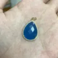 Detaillierte Nahaufnahme des blauen Tropfenanhängers mit Zirkonrand und Goldfassung. - S1-11